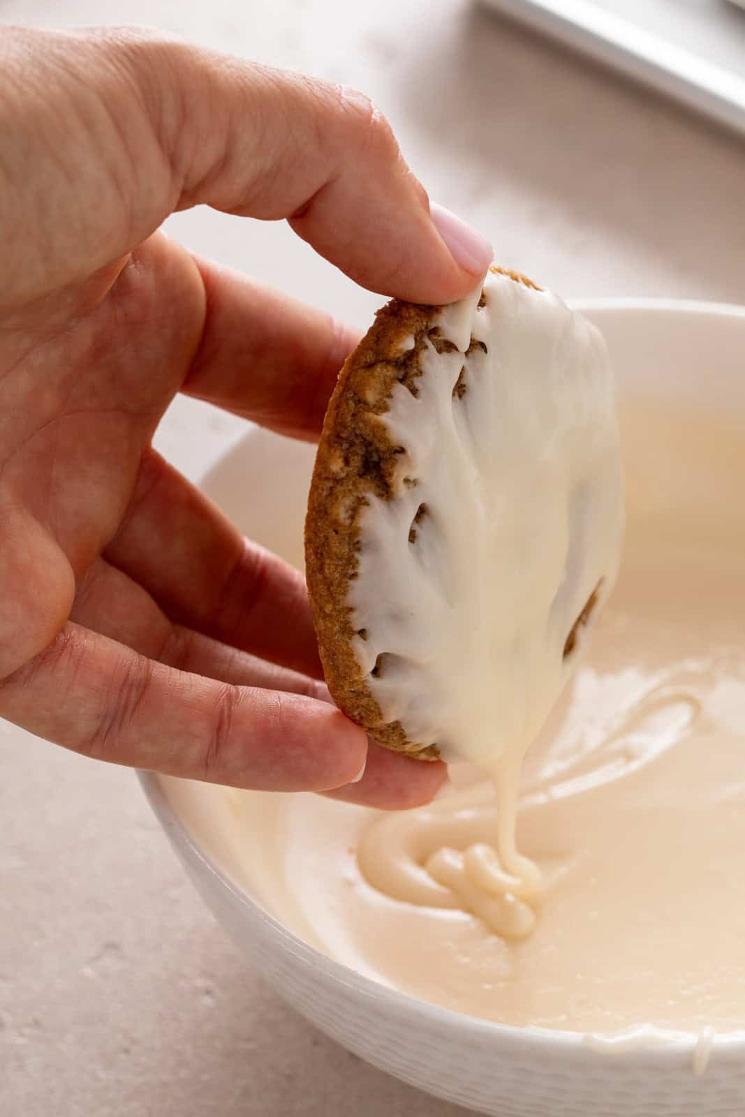Oatmeal cookie being dipped in icing.