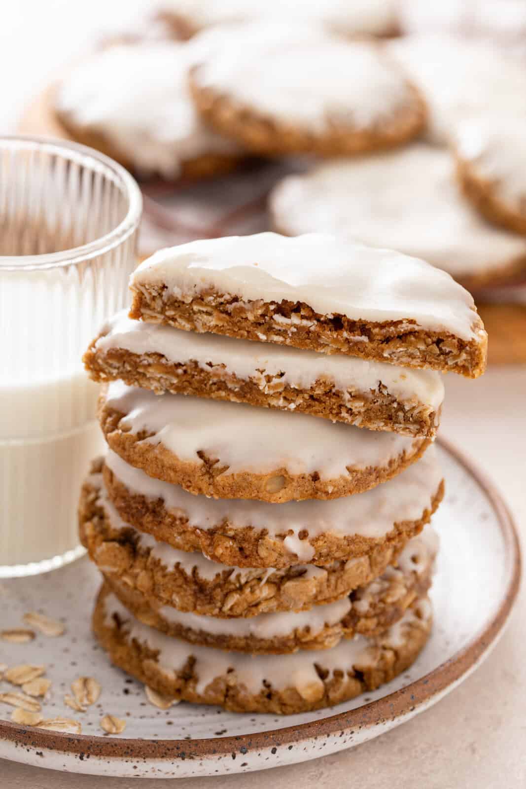 Halved iced oatmeal cookie resting on top of a stack of the cookies.