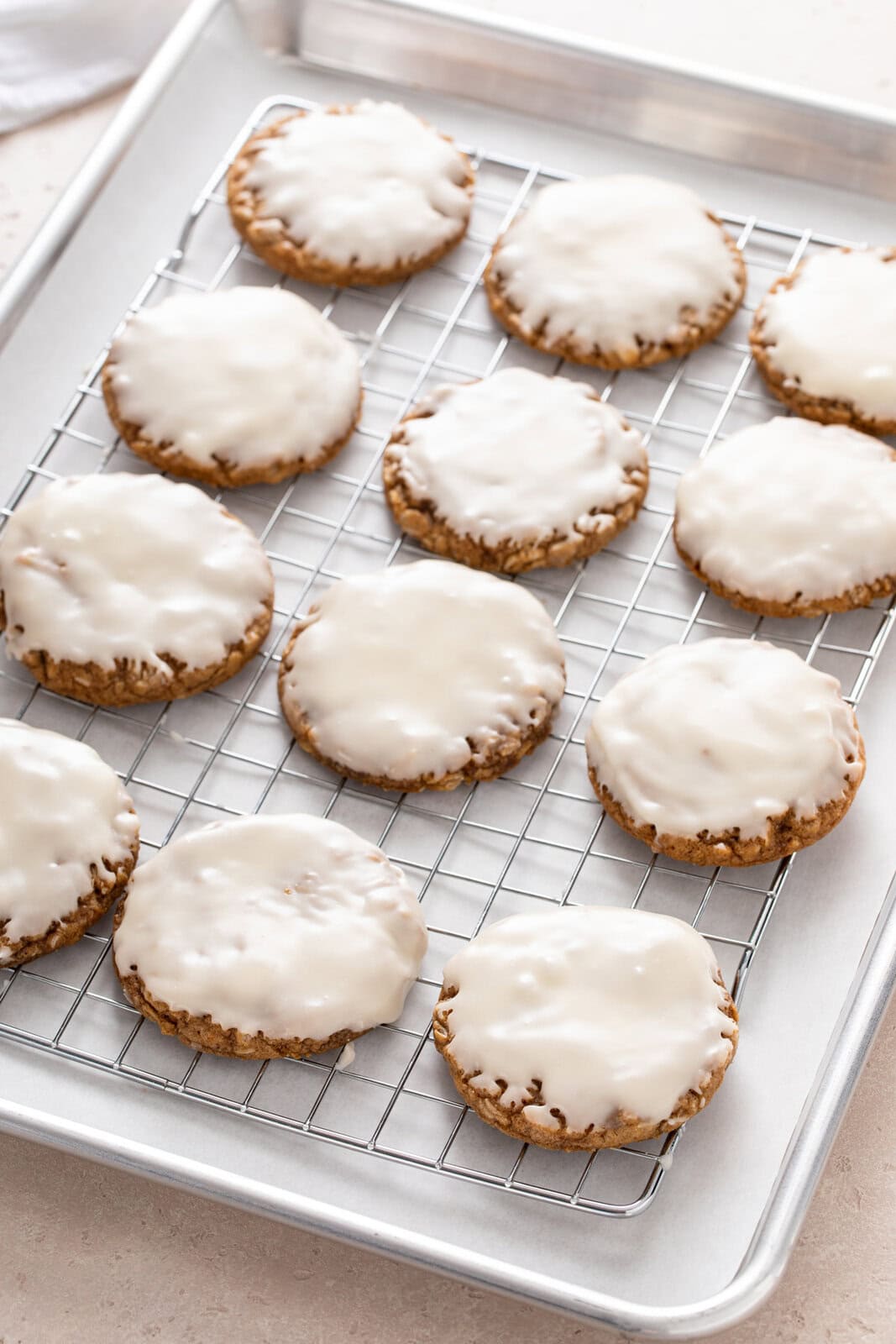 Iced oatmeal cookies resting on a wire rack.