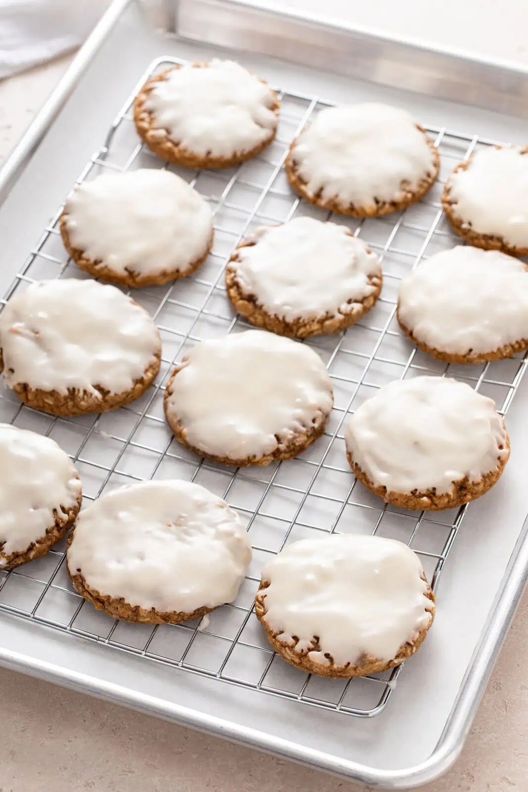 Iced oatmeal cookies resting on a wire rack.
