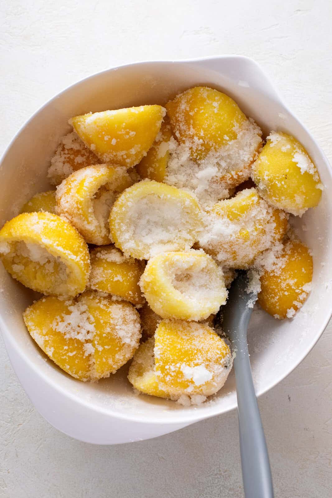 Spent lemon rinds and granulated sugar mixed in a bowl.
