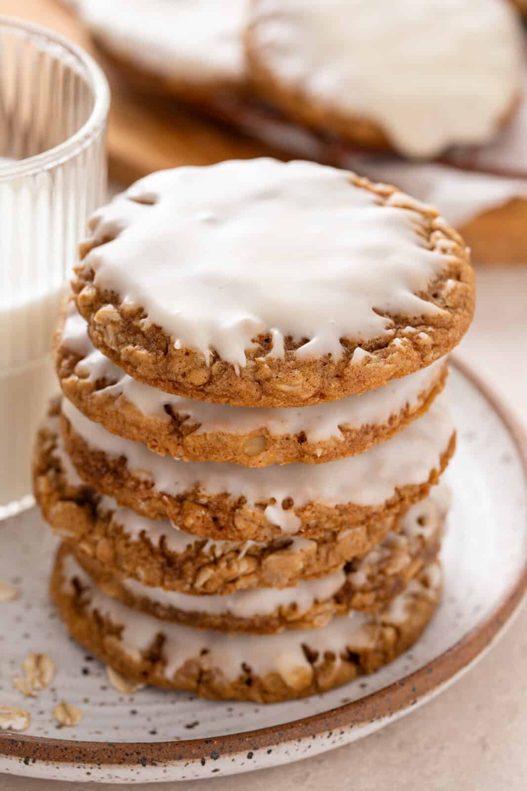 Stack of iced oatmeal cookies next to a glass of milk.