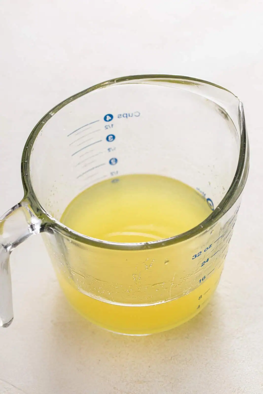 Strained lemon syrup in a glass measuring cup.