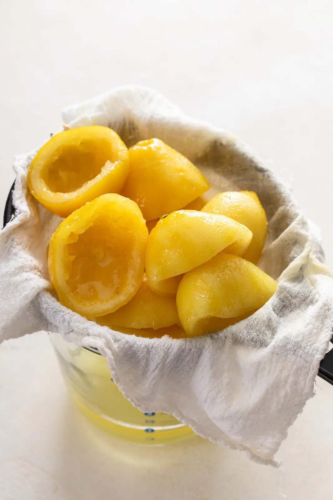 Easy lemon syrup being strained into a measuring cup.