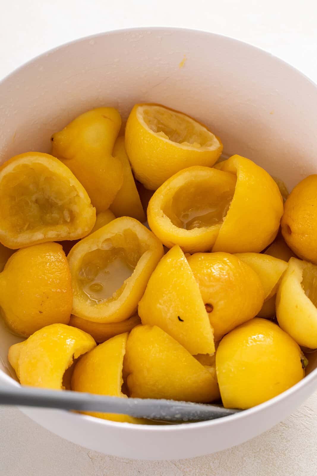 Syrupy spent lemon rinds in a large bowl.