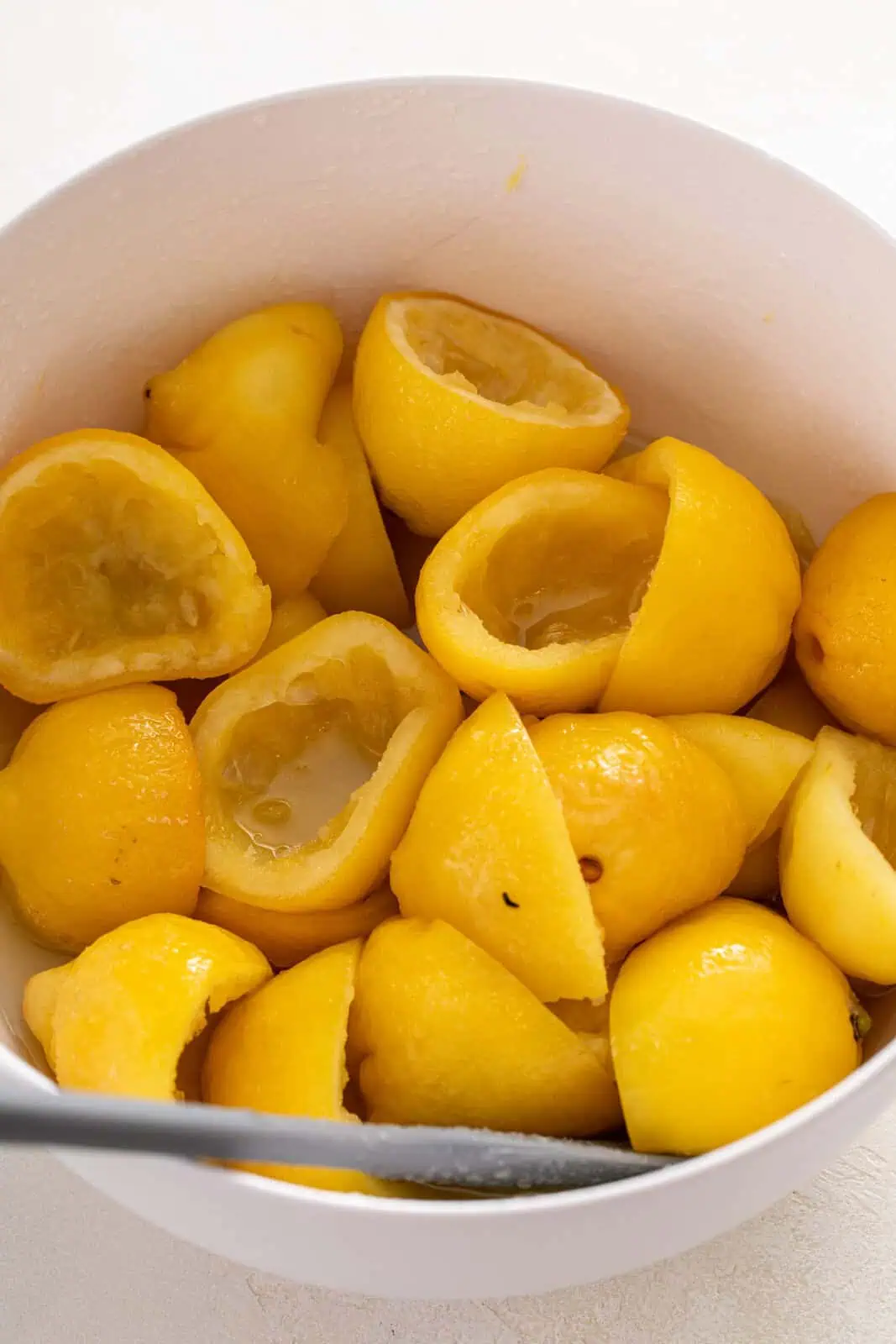 Syrupy spent lemon rinds in a large bowl.