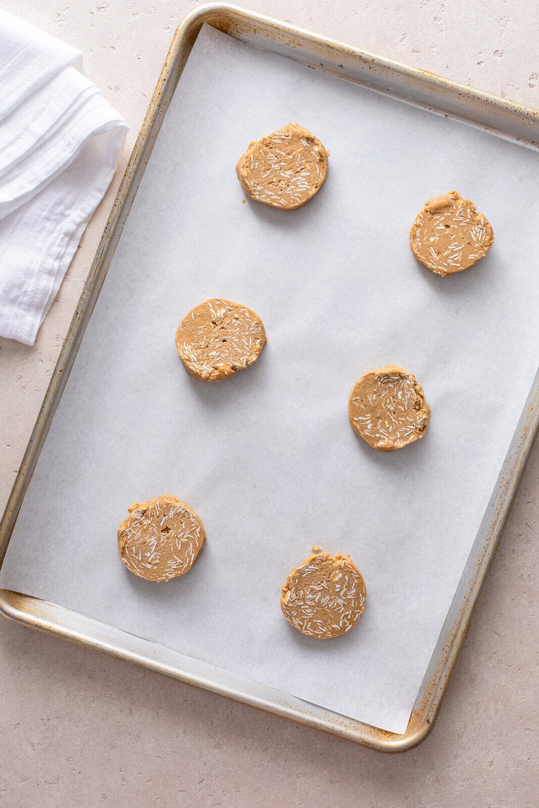 Unbaked oatmeal cookies on a parchment-lined sheet pan, ready to go in the oven.