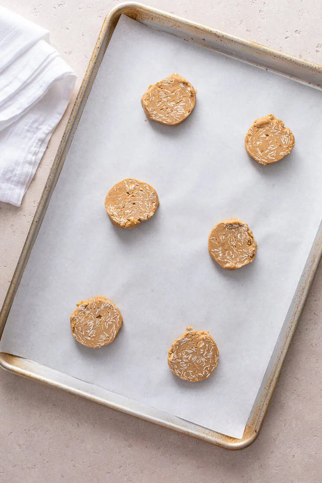 Unbaked oatmeal cookies on a parchment-lined sheet pan, ready to go in the oven.