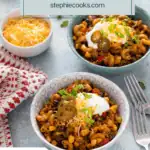 Two bowls, each holding servings of enchilada pasta topped with sour cream, cheese, and pickled jalapeños. Text overlay includes recipe name.