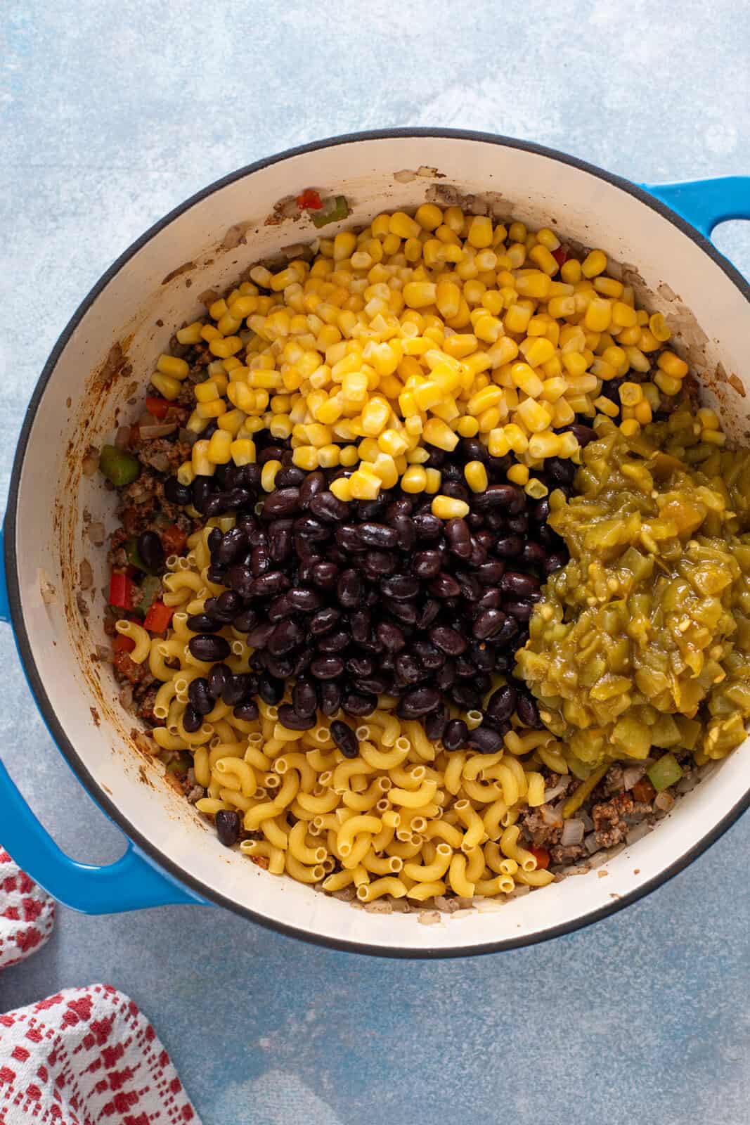 Corn, black beans pasta, and green chiles added to a dutch oven.