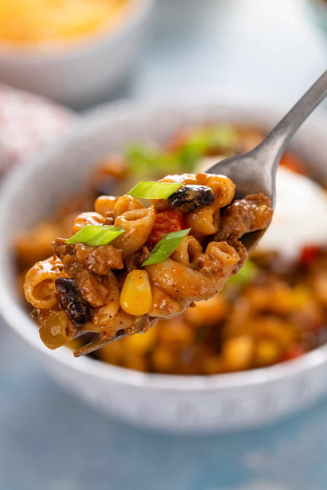 Fork holding up a bite of enchilada pasta.