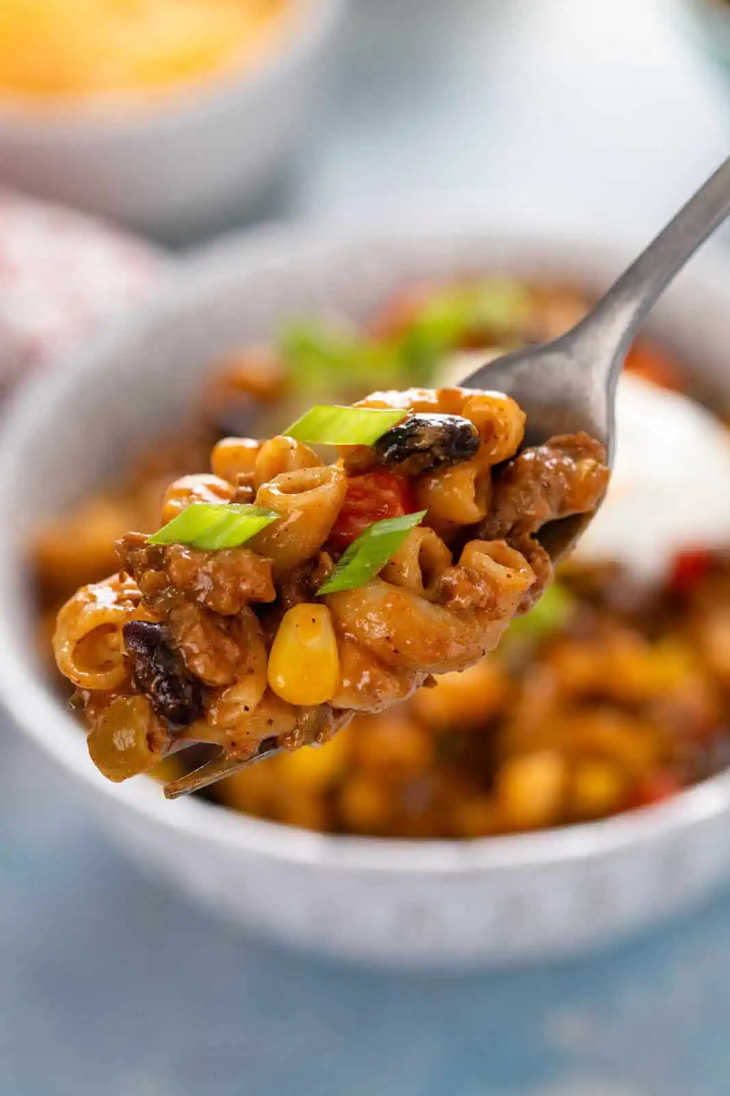 Fork holding up a bite of enchilada pasta.