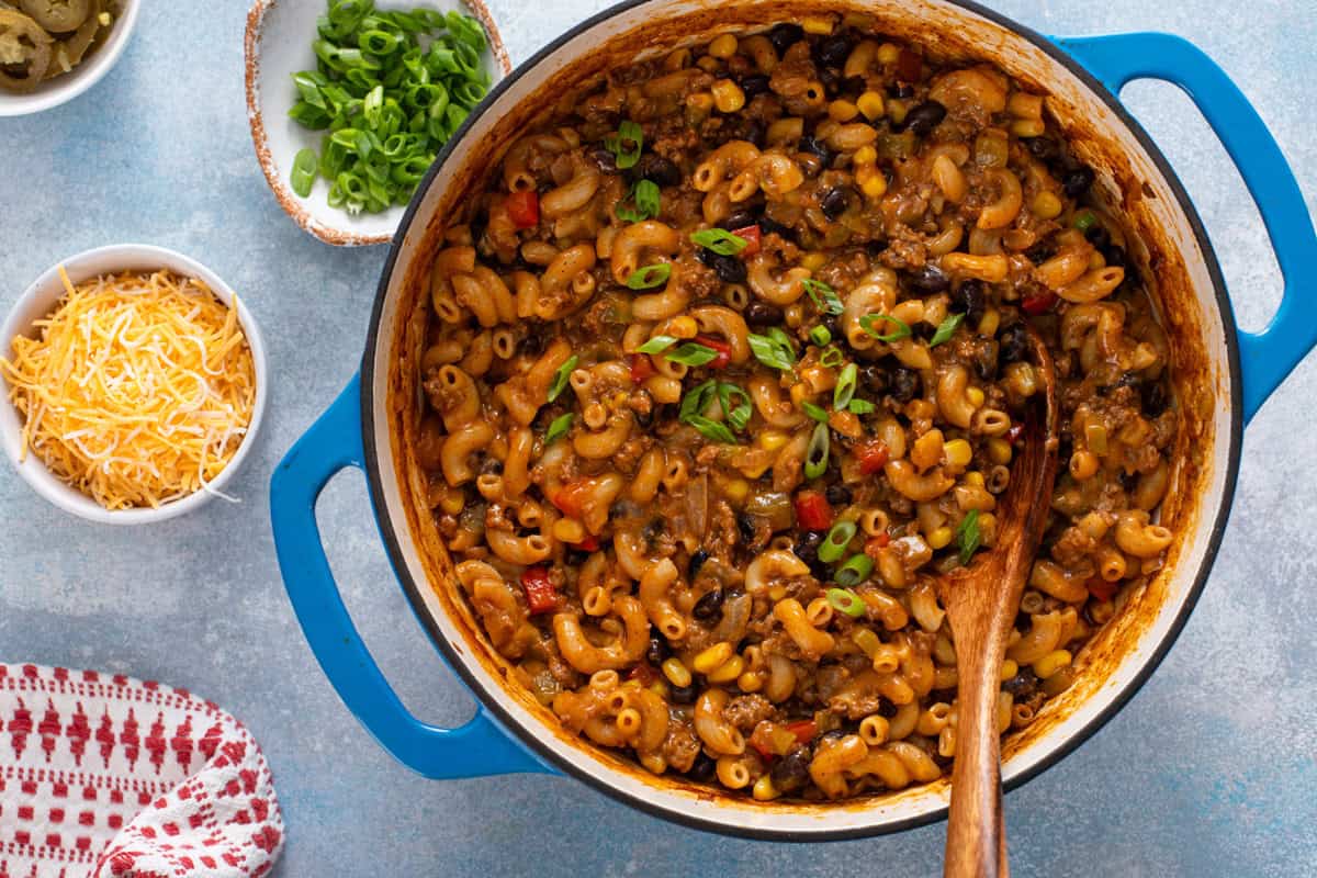 Overhead view of finished enchilada pasta in a dutch oven, garnished with green onions.