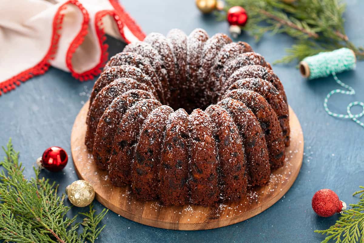 Old-fashioned fruitcake on a serving platter, dusted with powdered sugar.
