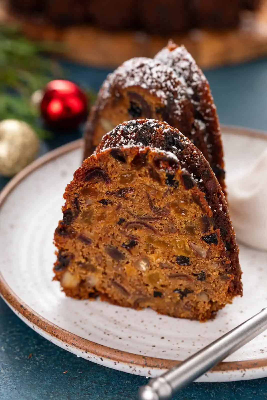 Two plated slices of old-fashioned fruitcake.