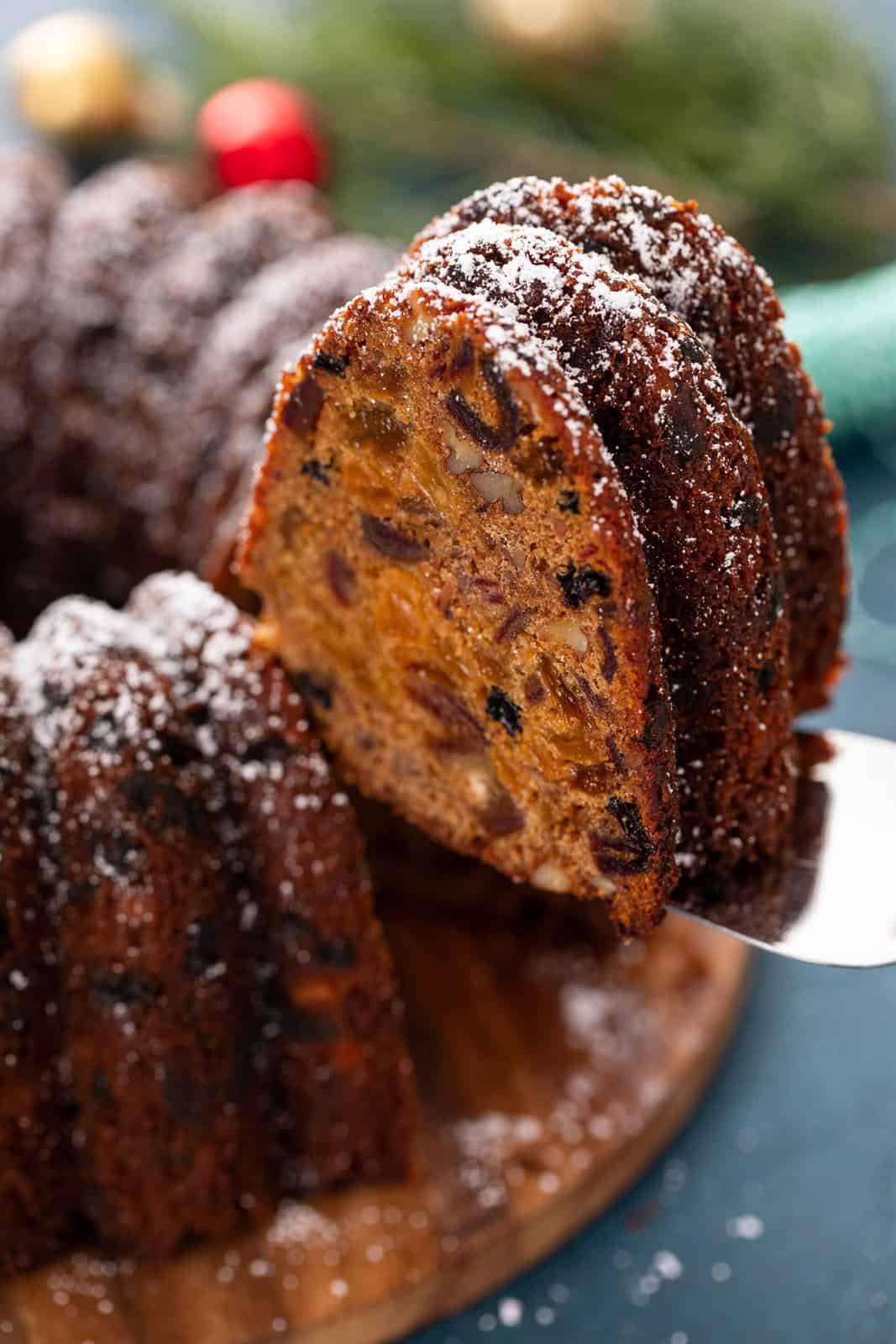 Slice of old-fashioned fruitcake being lifted up with a cake server.