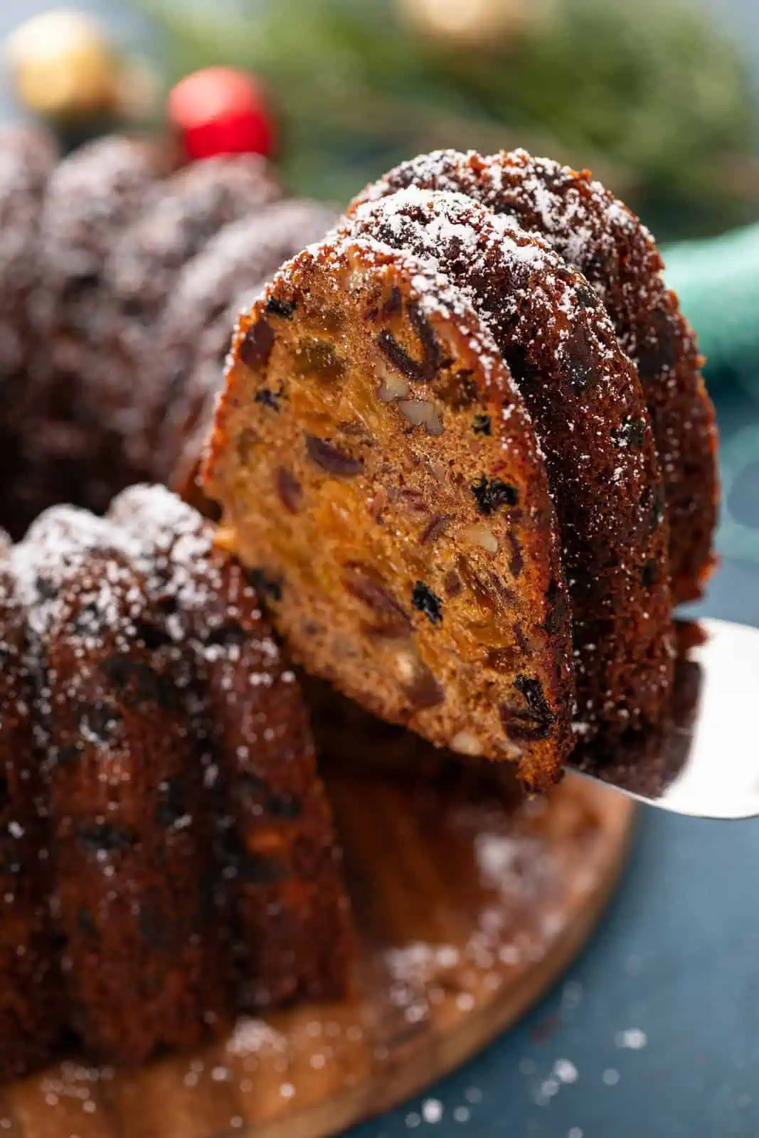 Slice of old-fashioned fruitcake being lifted up with a cake server.