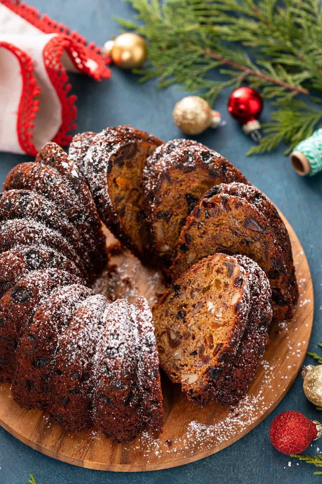 Sliced fruitcake on a wooden serving platter.