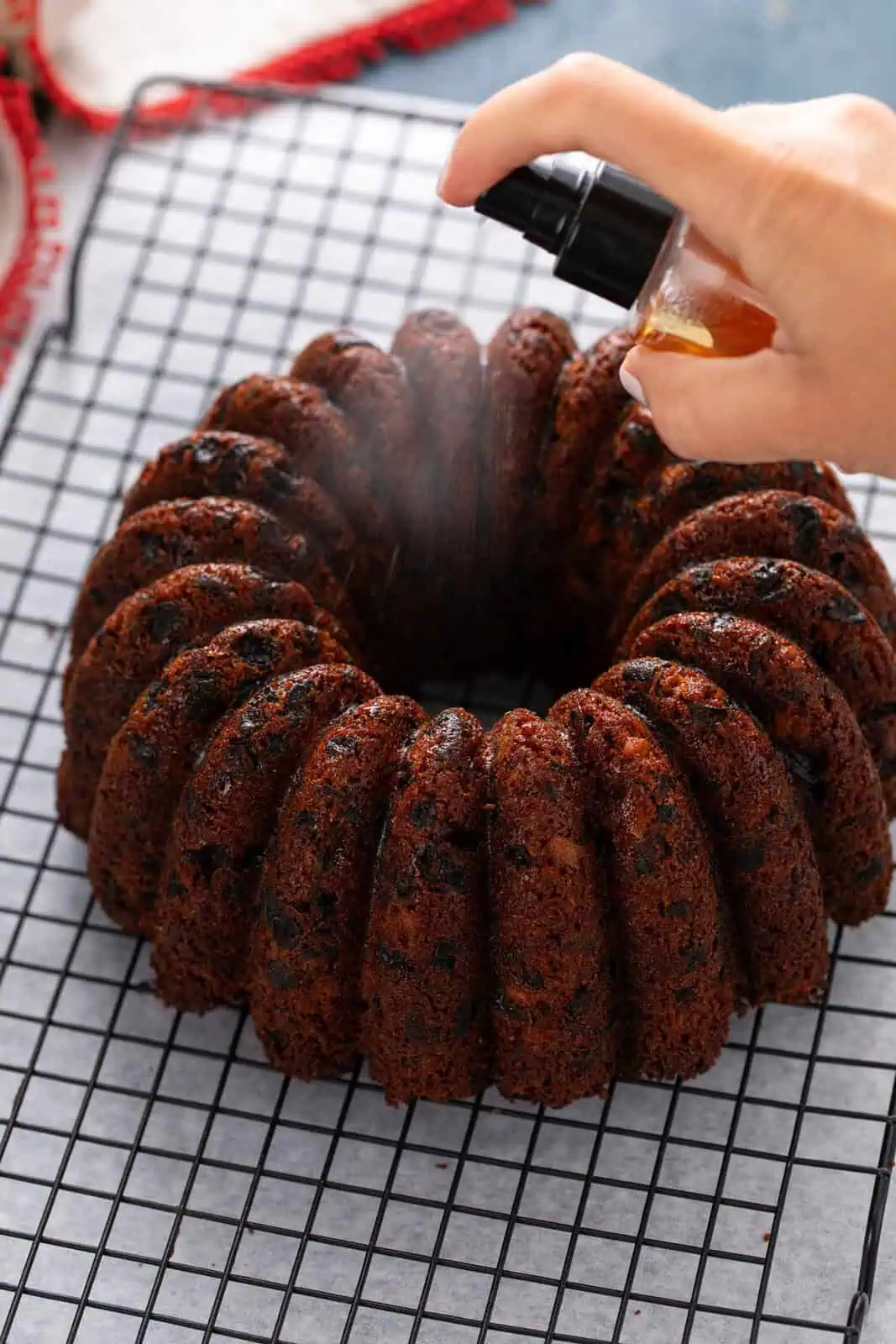 Cooled fruitcake being spritzed with brandy.