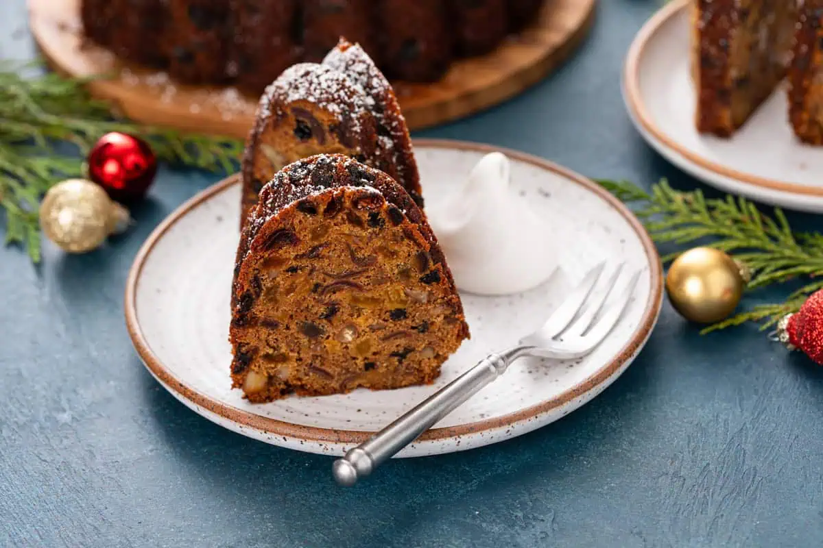 Plate holding two slices of fruitcake and a dollop of whipped cream.