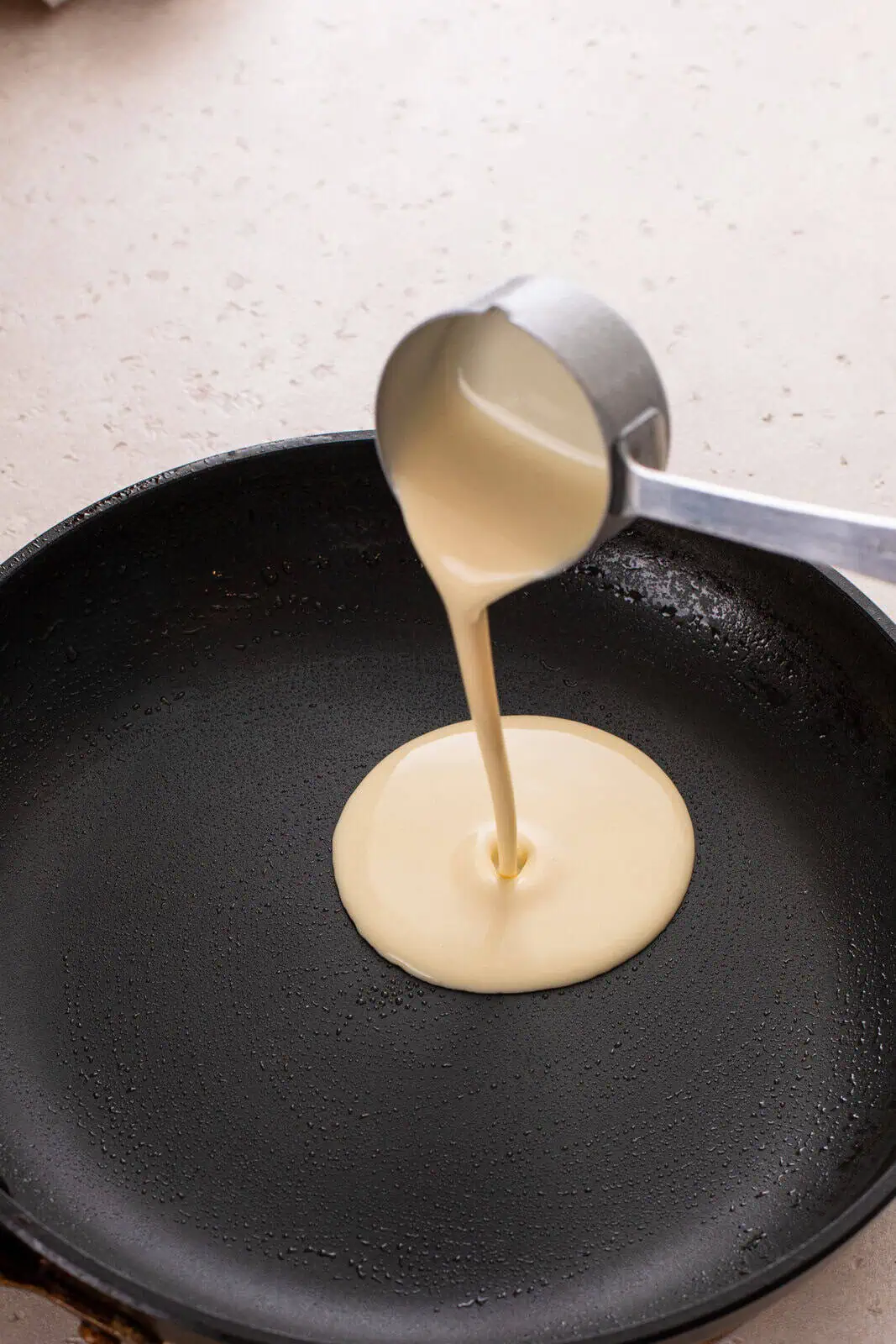 Crepe batter being poured into a skillet.