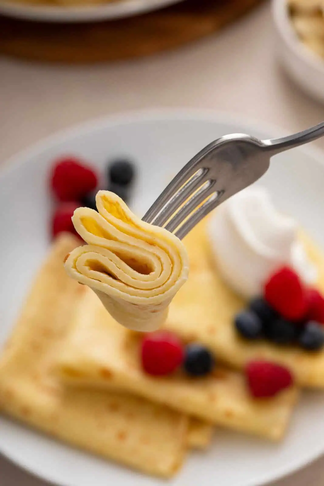 Fork holding up a bite of crepe.