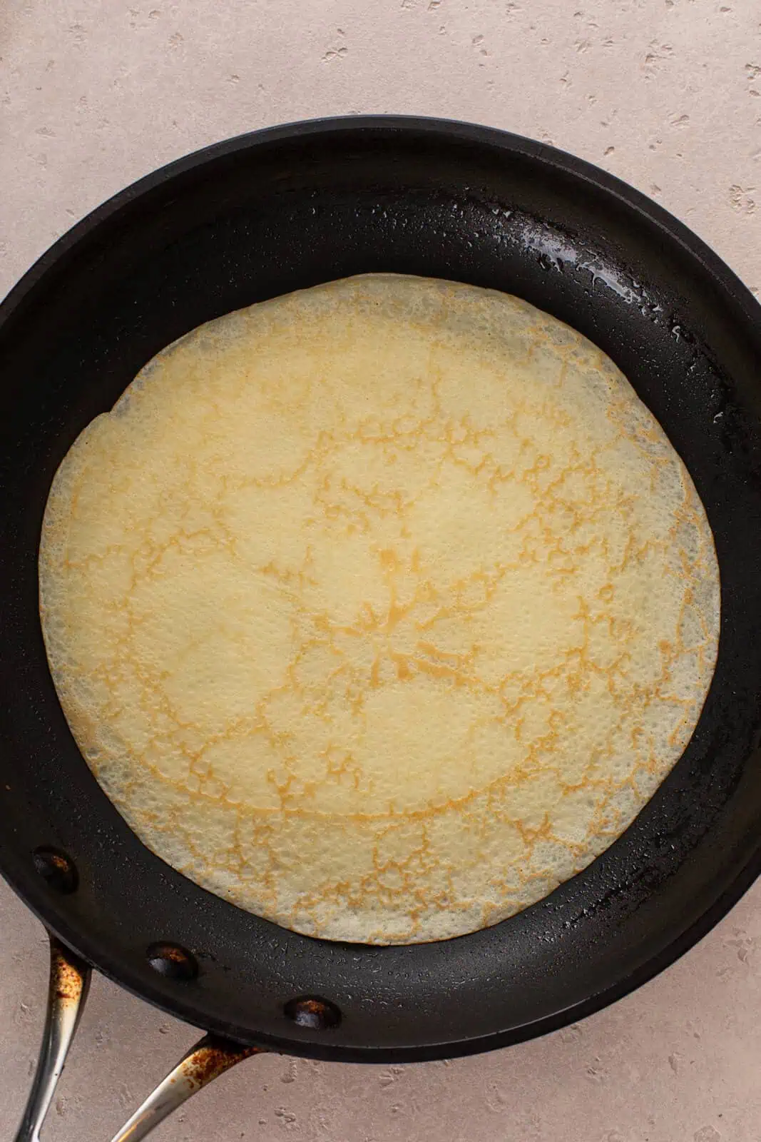 Flipped crepe cooking in a skillet.