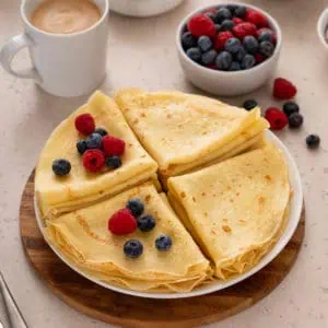 Crepes folded and stacked on a white platter.