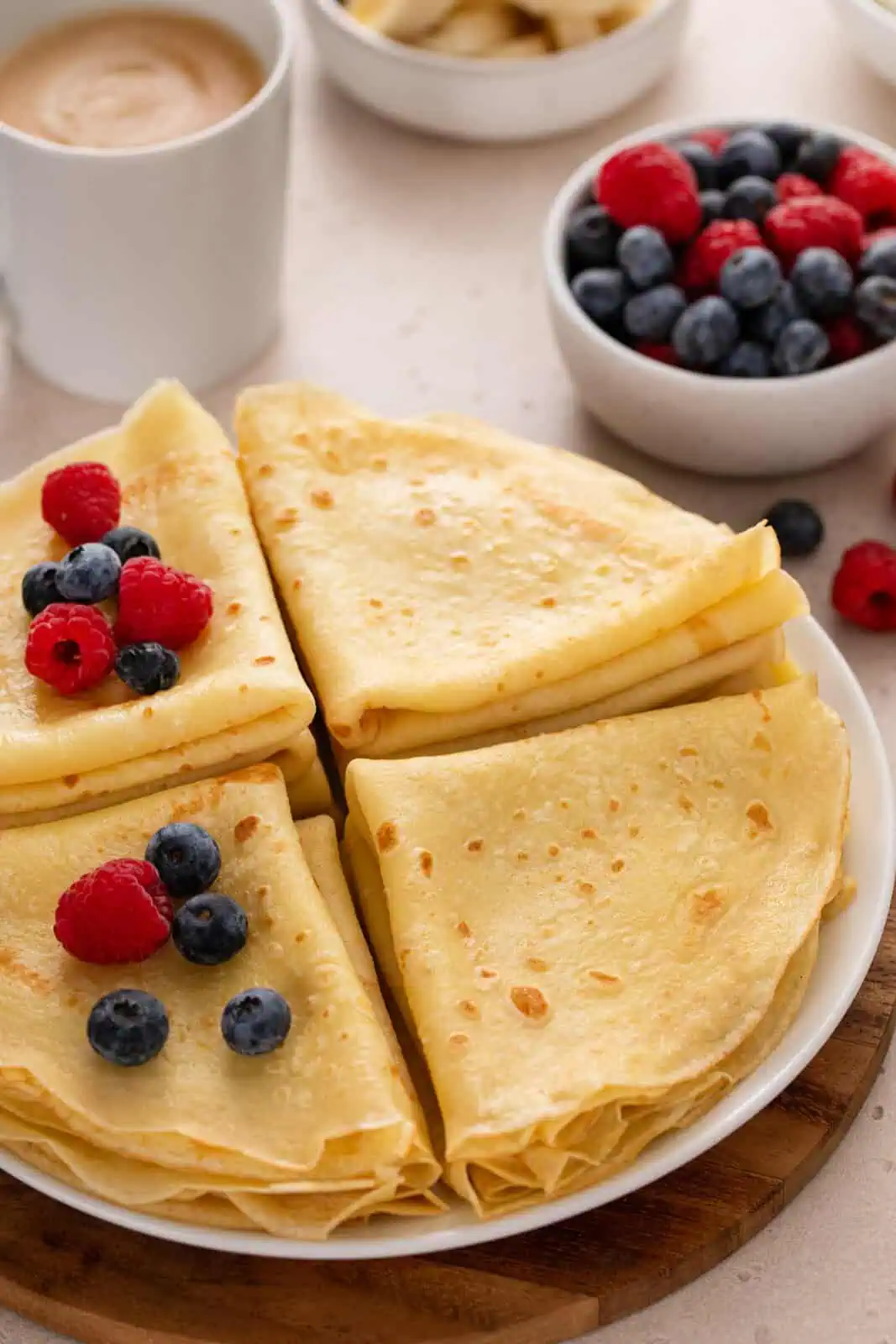 Close up of cooked and folded crepes stacked on a platter.