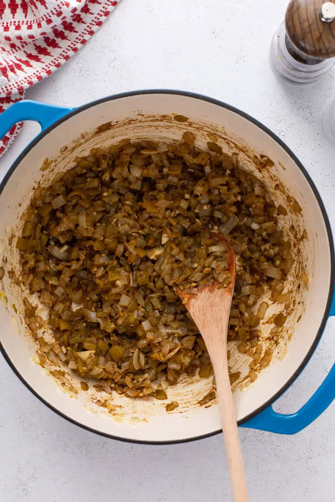 Onion, garlic, green chiles, and spices being sauteed in a dutch oven.