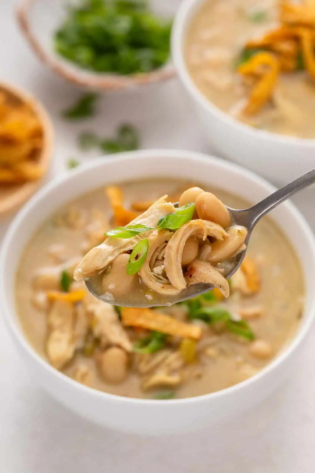 Spoonful of white bean chicken chili over a bowl of the chili.