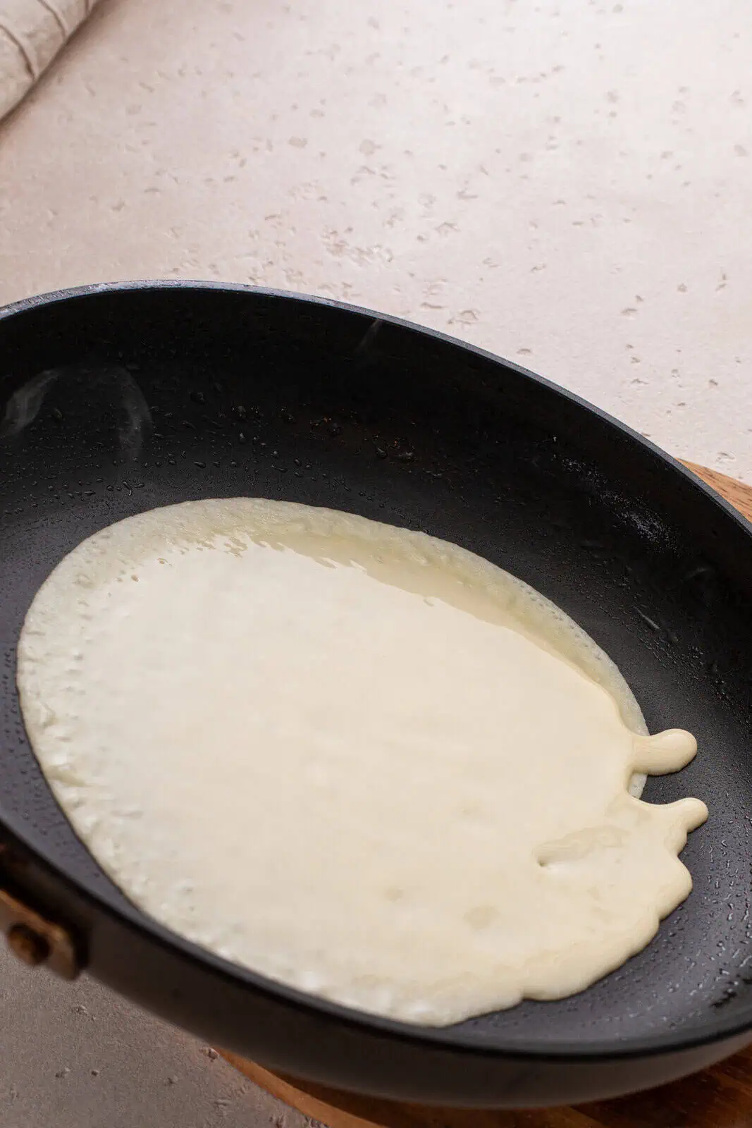 Finishing swirling crepe batter in a skillet.