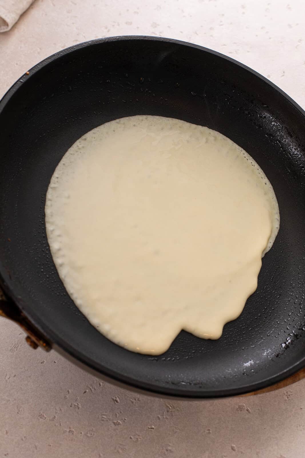 Crepe batter being swirled in a skillet.