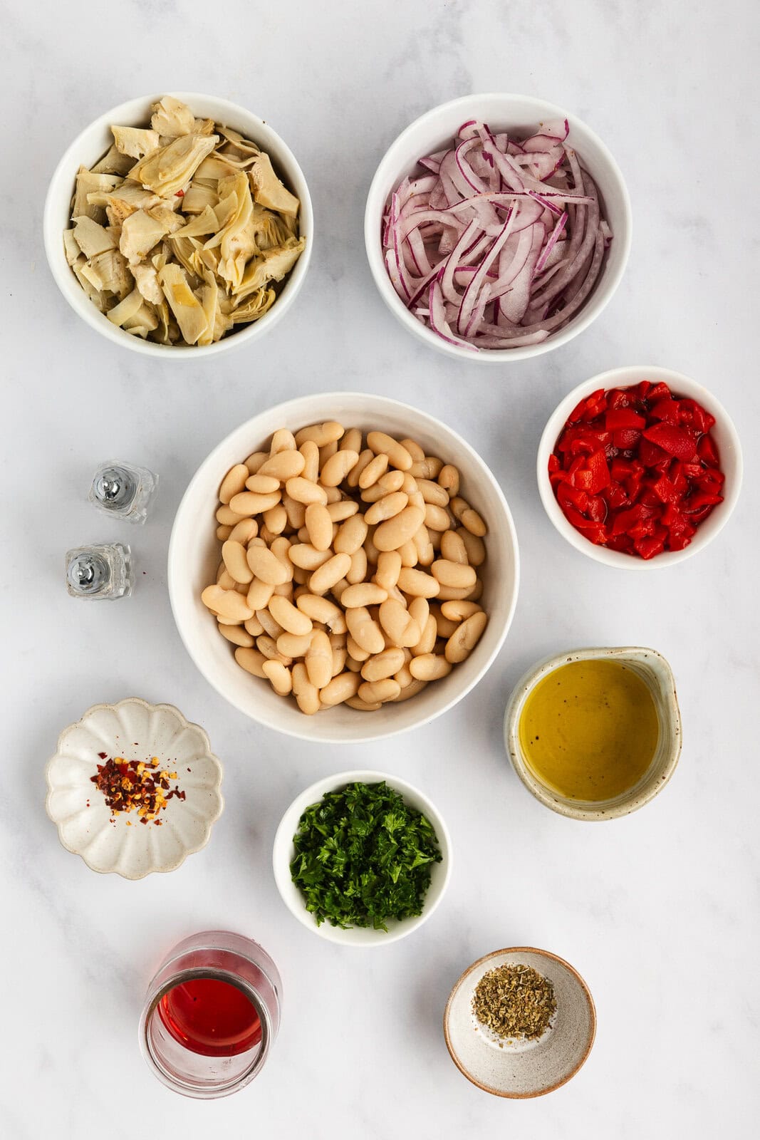 Ingredients for white bean and artichoke salad arranged on a countertop.