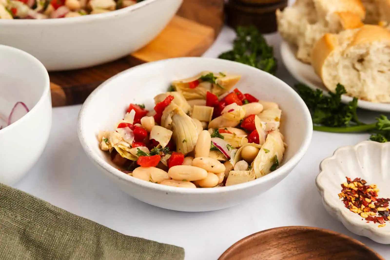 Small white bowl filled with white bean and artichoke salad.
