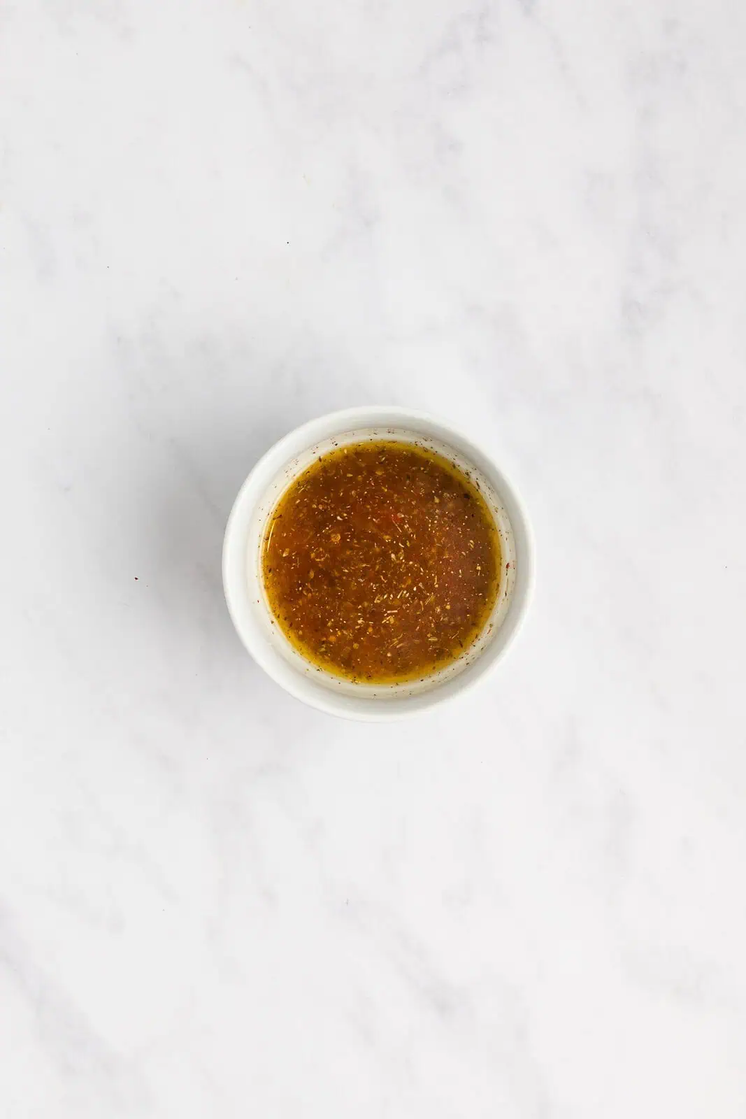 Dressing for white bean salad mixed in a small bowl.