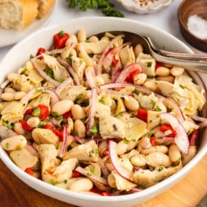 White bean and artichoke salad in a white serving bowl.