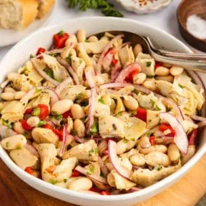 White bean and artichoke salad in a white serving bowl.