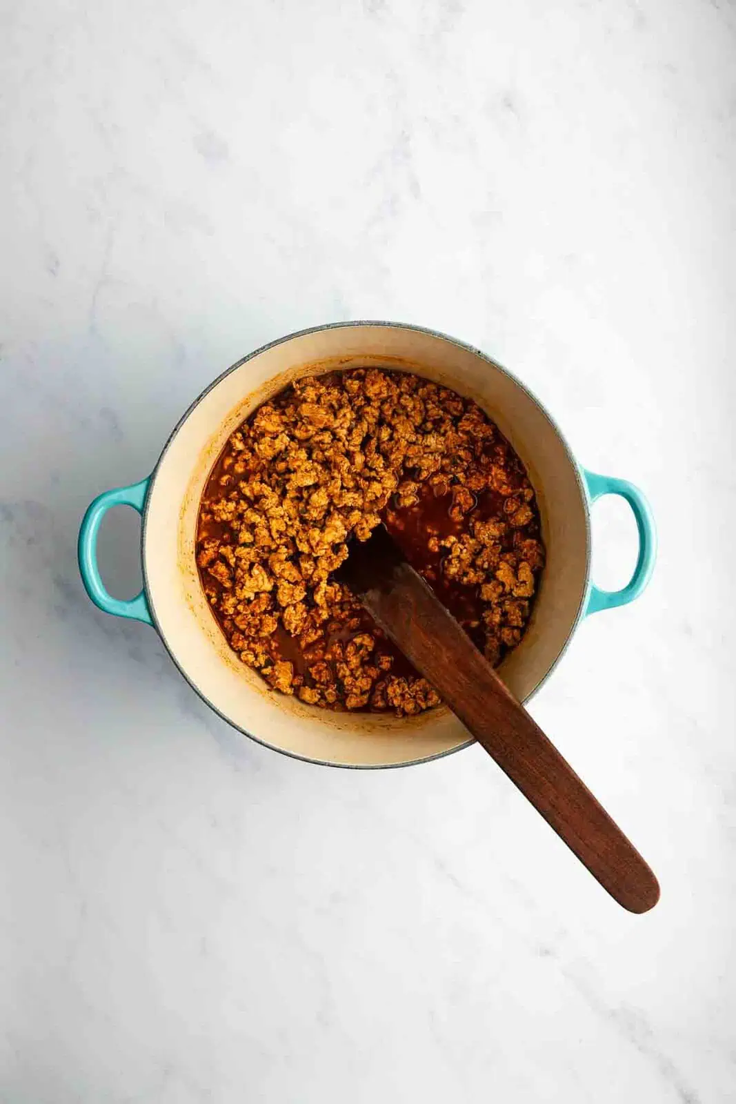 Tomato paste and spices added to ground turkey in a dutch oven.