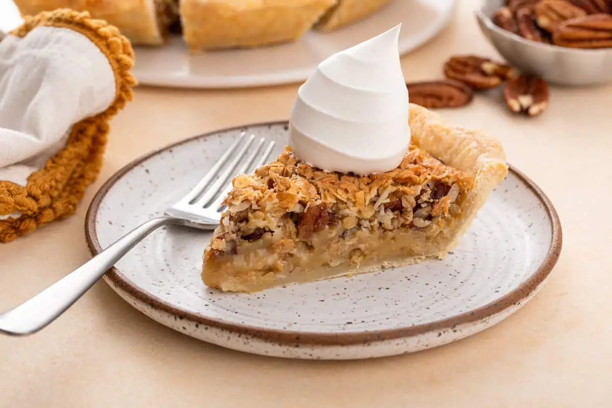 Slice of oatmeal pie on a plate, topped with a dollop of whipped cream.