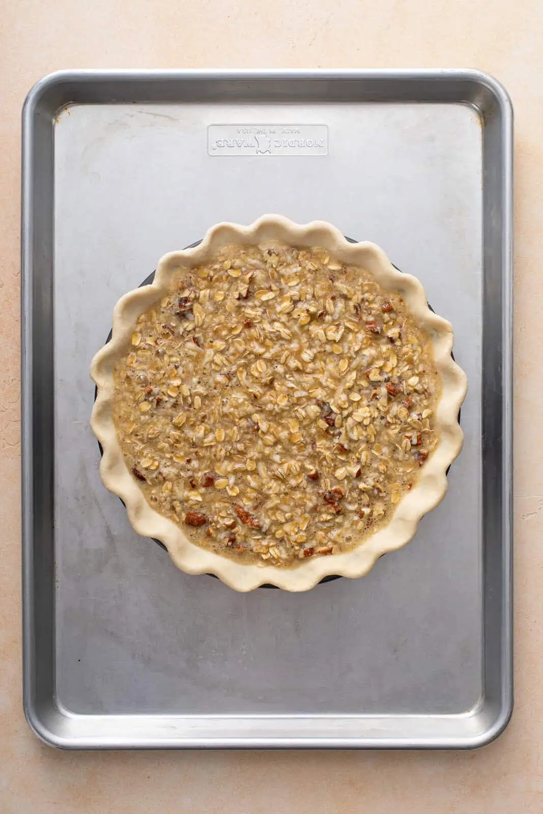 Unbaked oatmeal pie on a rimmed baking sheet, about to go in the oven.