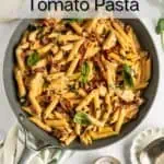 Overhead view of chicken and sun-dried tomato pasta in a skillet, garnished with fresh basil. Text overlay includes recipe name.