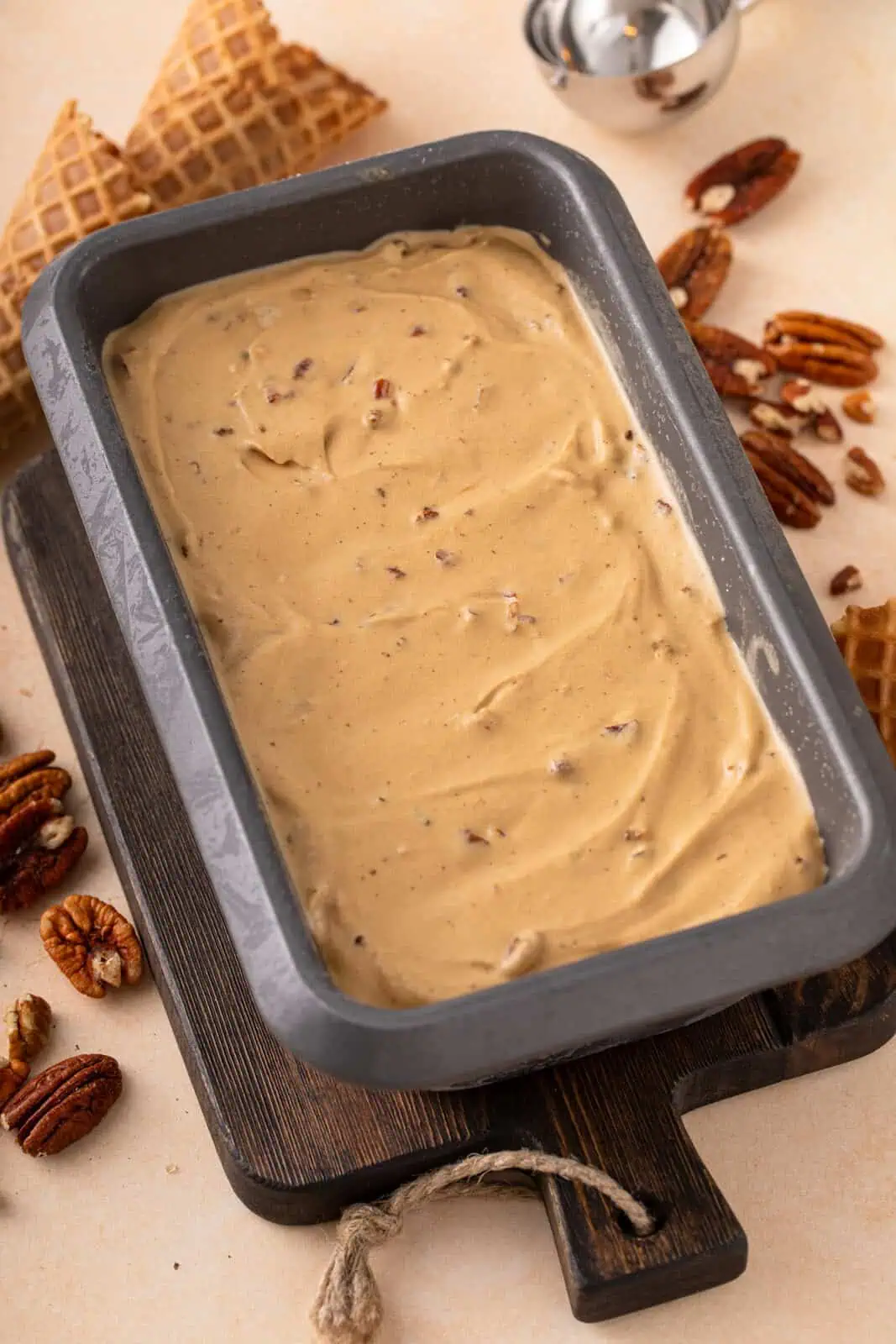 Churned butter pecan ice cream spread into a container for freezing.