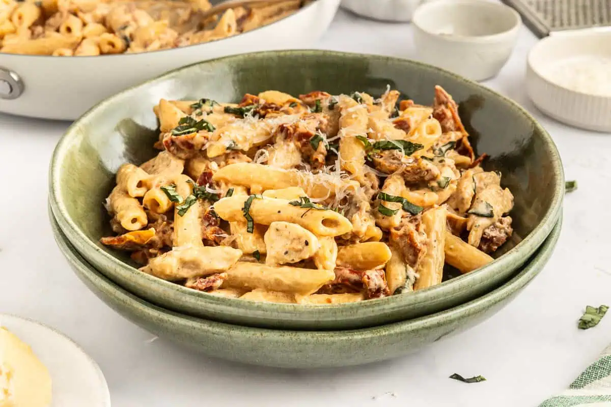 Sun-dried tomato pasta in a shallow green pasta bowl.