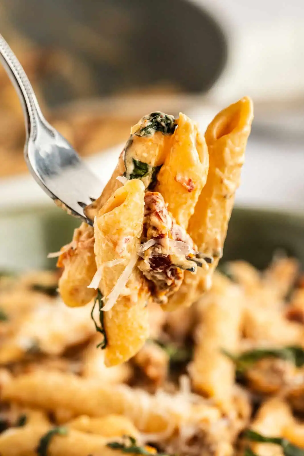 Fork holding up a bite of sun-dried tomato pasta.