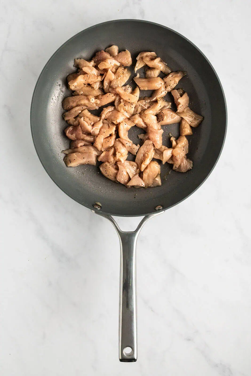 Seared pieces of chicken in a skillet.