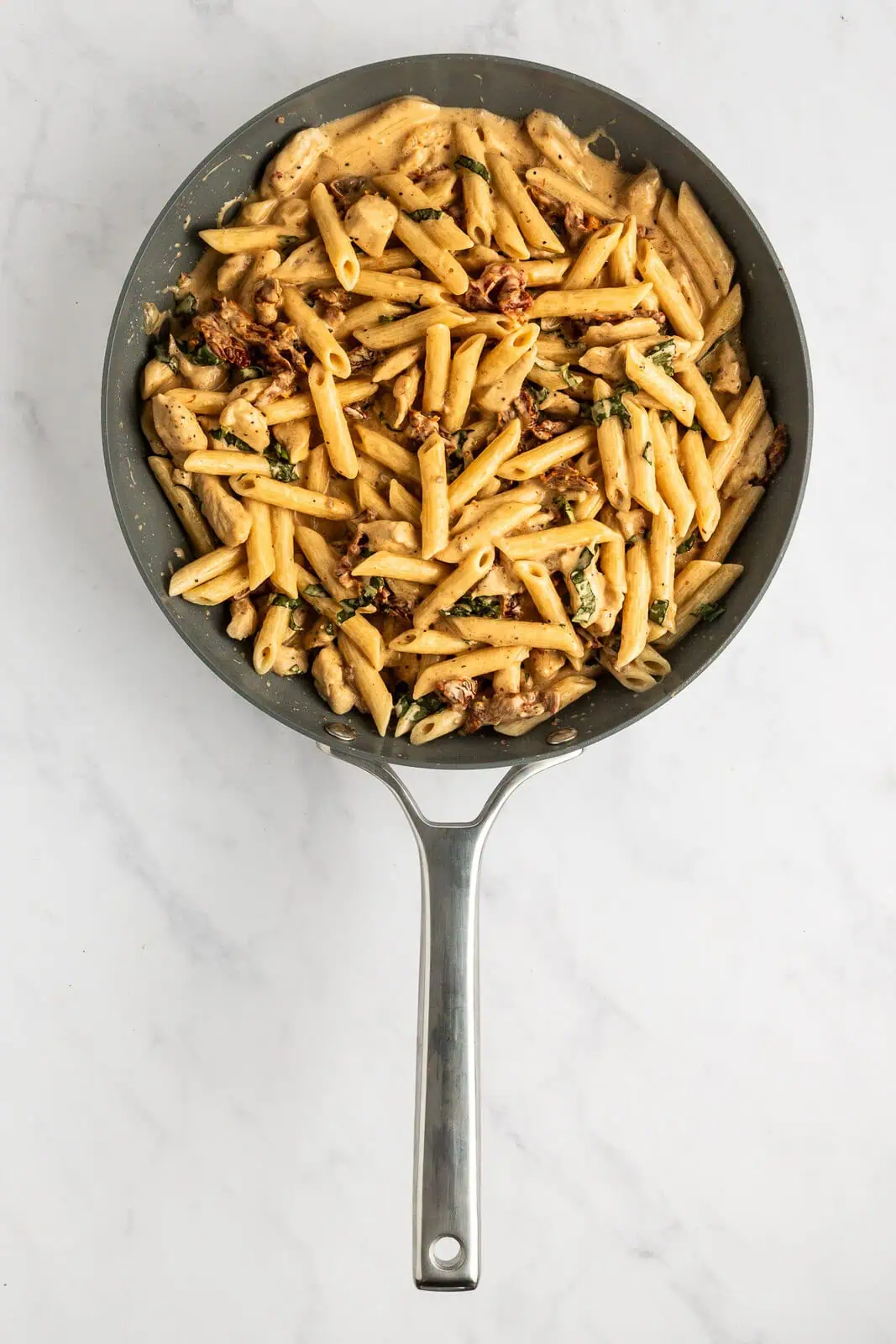 Finished sun-dried tomato pasta in a skillet.