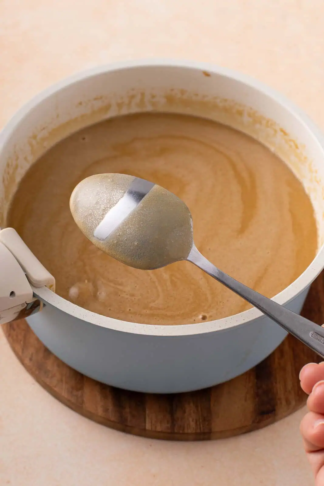 Back of a spoon showing the thickened texture of butter pecan ice cream base.