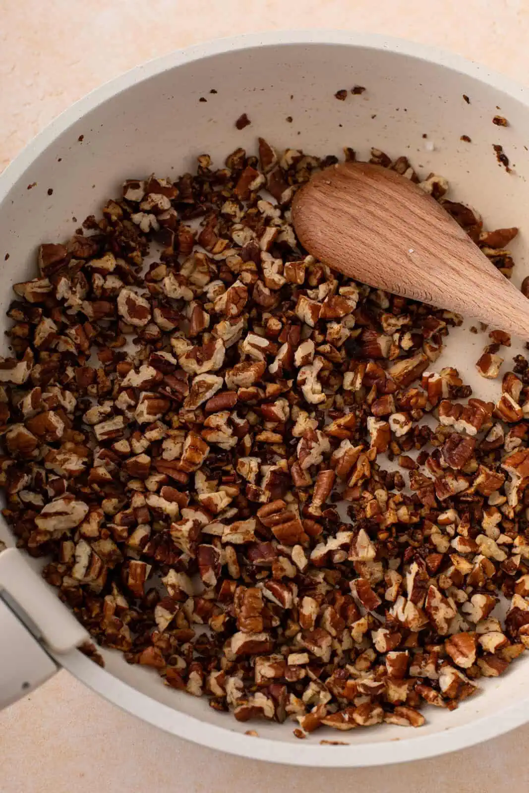 Toasted pecans for butter pecan ice cream being stirred in a skillet.