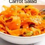 Side view of white bowl filled with shaved carrot salad, with a fork tucked into the bowl. Text overlay includes recipe name.